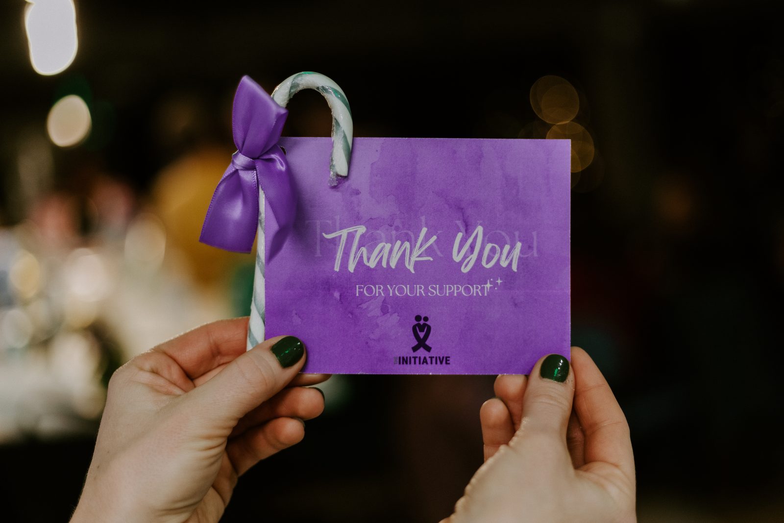 Hands holding a purple card that reads Thank you for your support
